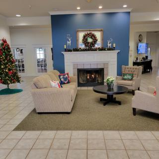 A cozy living room decorated for the holidays with a fireplace and Christmas tree.