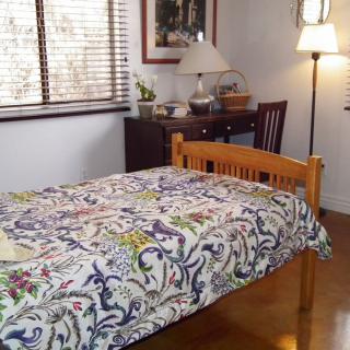 A cozy bedroom with a patterned bedspread and wooden furniture.
