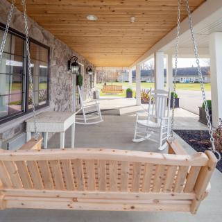 A cozy porch with a wooden swing and rocking chairs under a covered patio.