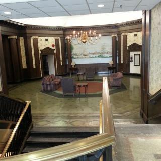 A stylish lobby featuring a central seating area, elegant wood paneling, and a chandelier.