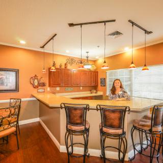 A modern kitchen with a bar area featuring stylish seating and warm orange walls.