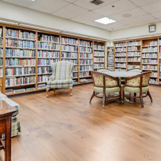 A quiet library reading room with shelves full of books and comfortable seating.