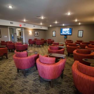 A cozy lounge with red chairs and a television on the wall.