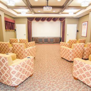 A cozy theater room with patterned armchairs arranged towards a large projector screen.