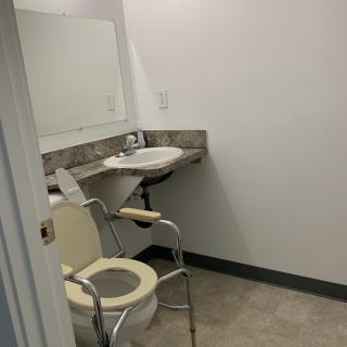Accessible bathroom with a toilet chair and sink.