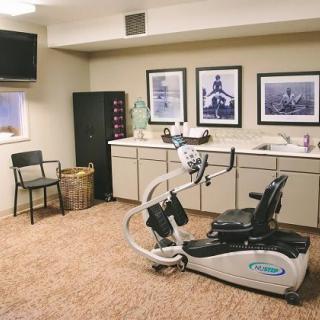 A cozy exercise room equipped with a stationary bike, television, and decorative artwork on the walls.