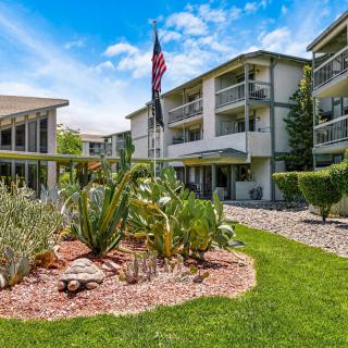 A sunny day at a landscaped apartment complex with a flag and well-maintained gardens.