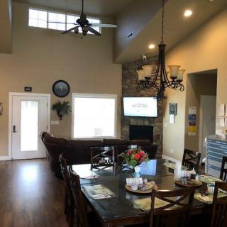 A cozy living room with high ceilings, featuring a dining table, sofa, television, and a decorative chandelier.