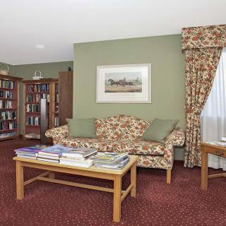 A cozy living room with a floral sofa, bookshelf, and coffee table.
