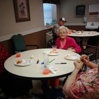 Elderly individuals enjoying a meal together in a retirement home setting.