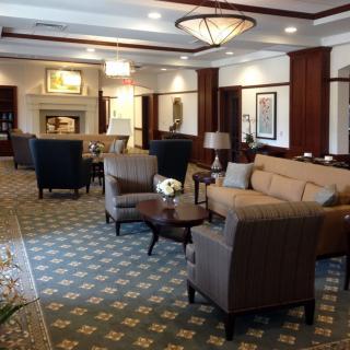 A luxurious hotel lobby with elegant furniture, a patterned carpet, and ornate chandeliers.
