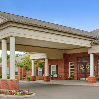 A brick building with a covered entrance supported by columns.