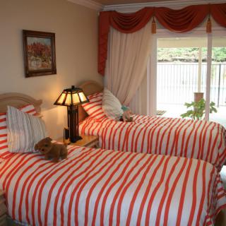 A cozy bedroom with twin beds featuring red and white striped bedding.
