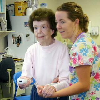 A caregiver assisting an elderly woman in a healthcare setting.
