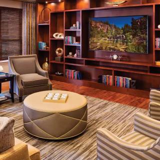 A cozy living room with elegant furniture and a built-in TV surrounded by bookshelves.