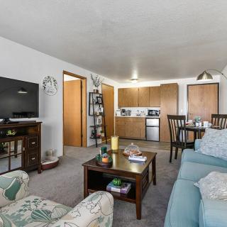 A cozy living room with a view of the kitchen area, featuring comfortable seating and modern appliances.