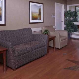 A cozy waiting room with a sofa, armchair, and wall art.