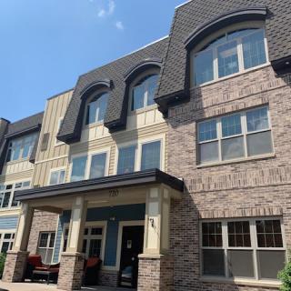 A multi-story residential building with a modern design featuring large windows and textured facade.