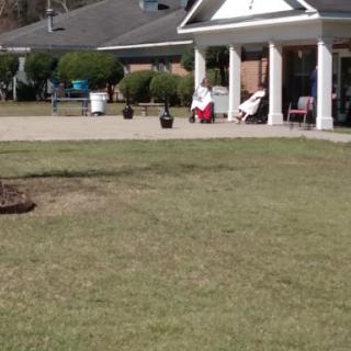 A peaceful afternoon scene on the porch of a house, where two individuals are enjoying the outdoors.