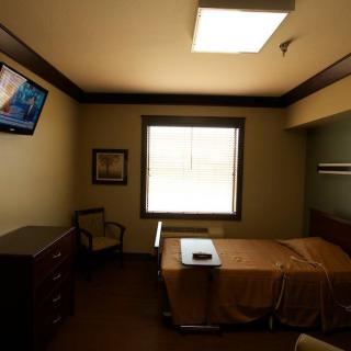 A hospital room with a bed, television, and window.