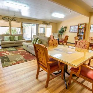 A cozy living and dining area with a sofa, chairs, and table set on wood flooring.