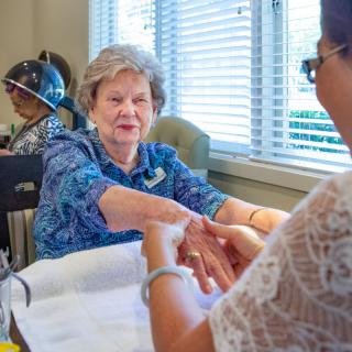 An elderly woman receiving a relaxing manicure at a spa salon.