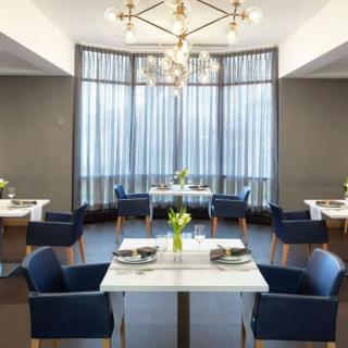 A modern restaurant interior with elegant dining tables and a striking chandelier.