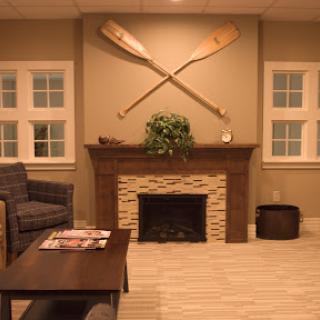 A cozy living room featuring a decorative fireplace, comfortable seating, and wooden paddles mounted on the wall.