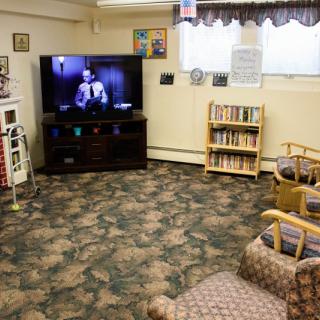 A cozy living room with a television and bookshelves filled with books.