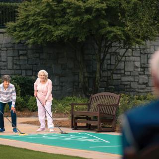 A group of seniors enjoying a game of shuffleboard outdoors.