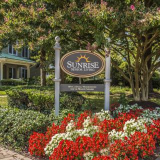 A well-maintained garden with vibrant flowers and a sign in front of a building.