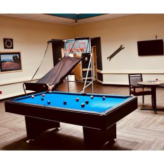 A recreational game room featuring a pool table and a basketball arcade game.