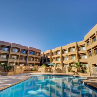 A modern resort with a spacious swimming pool under a clear blue sky.