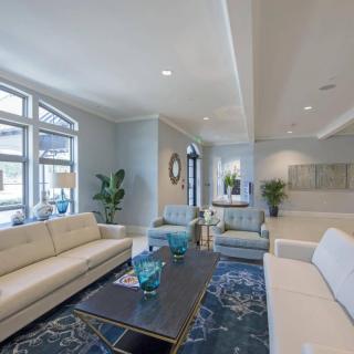 A modern living room with large windows, comfortable seating, and decorative elements.