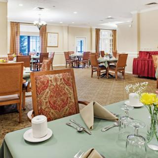 A well-decorated dining area with neatly set tables and chairs, featuring floral arrangements.