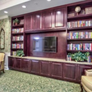 A cozy living room featuring a wooden entertainment center with a television, surrounded by bookshelves filled with books and decorative items.