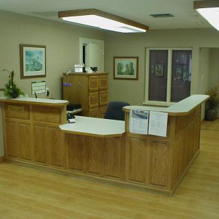 A reception office with a wooden desk and artwork on the walls.