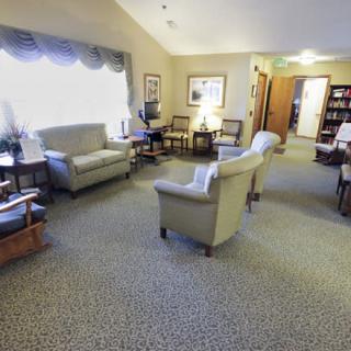 A cozy living room with comfortable chairs and a sofa arranged around a carpeted area.