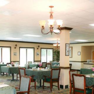 An empty dining room with neatly arranged tables and chairs, featuring a decorative chandelier.