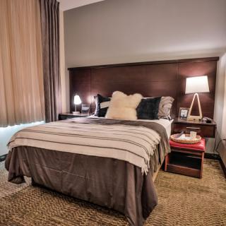 A cozy, well-decorated bedroom with a neatly made bed, warm lighting, and stylish decor.