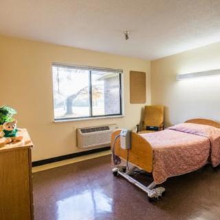 A simple hospital room with a single bed and window.