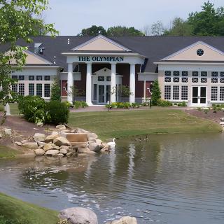 A scenic view of a building with a pond in the foreground.