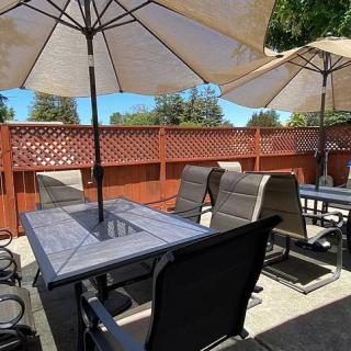 Sunny outdoor patio with tables, chairs, and umbrellas.