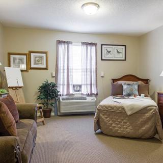 A cozy bedroom with a single bed, armchair, and tasteful decor.