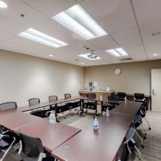 A modern conference room equipped for meetings with a large table and multiple chairs.