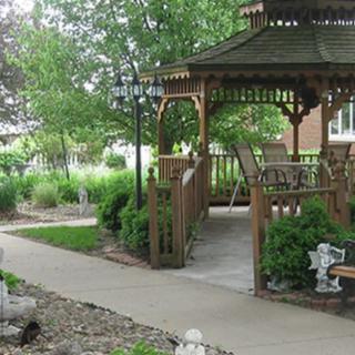 A serene garden setting with a wooden gazebo and surrounding greenery.