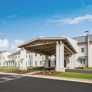 A modern building exterior with a covered entrance and a clear blue sky.