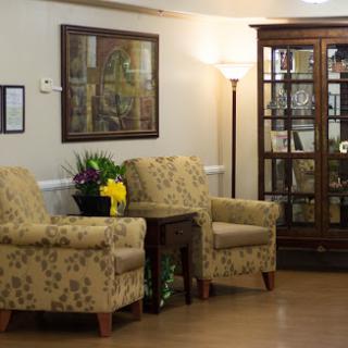 A cozy and inviting seating area featuring stylish floral-patterned chairs and a display cabinet.