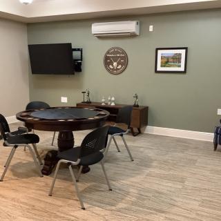 A cozy room featuring a poker table with chairs, a television, and decorative wall art.