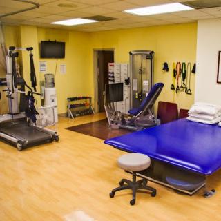 A well-equipped physical therapy clinic featuring various exercise machines and treatment areas.